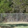 tall and secure chain link fence for property with grass and trees
